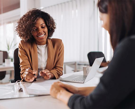 Two women chatting with papers at desk