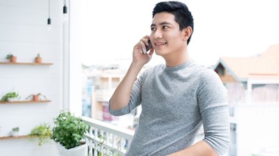 A man standing on a balcony talking on the phone