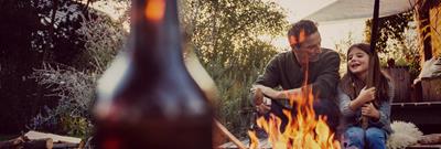 Father and daughter sit in garden in front of a fire pit